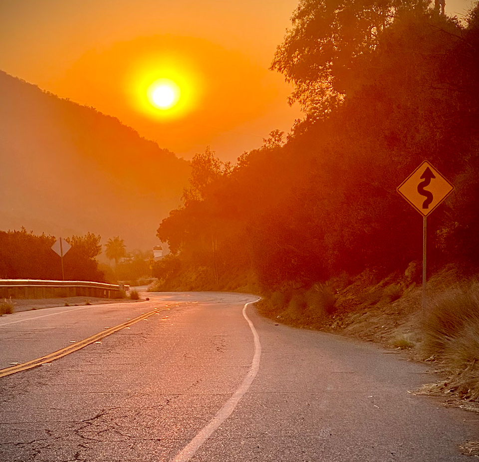 A road with the sun setting in the background.