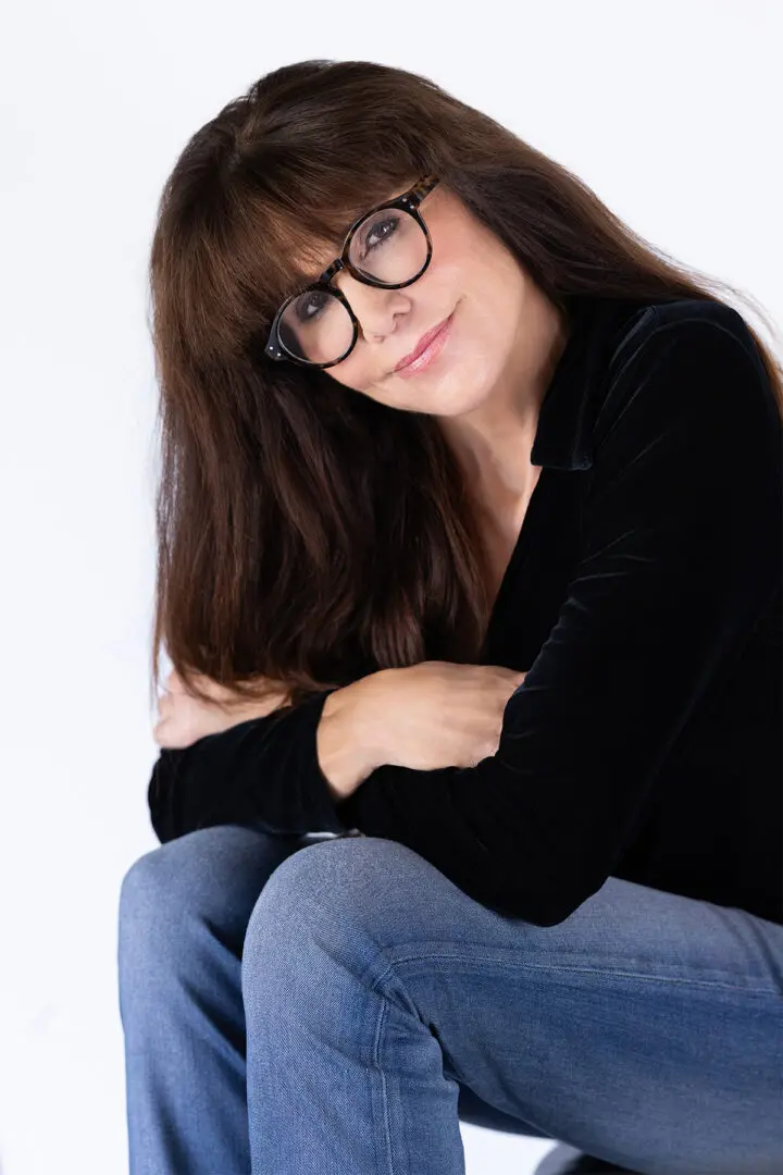 A woman sitting on the ground wearing glasses.